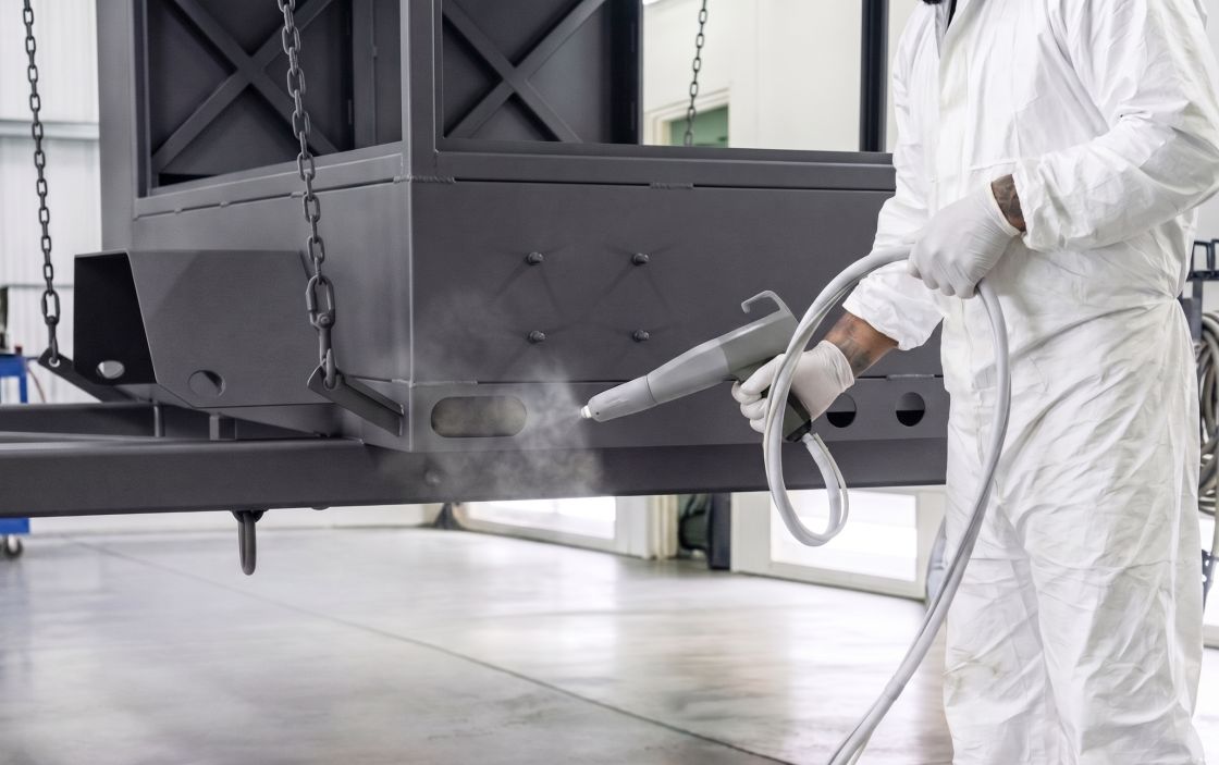 Operator spraying powder coating in a booth