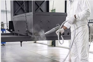 Operator spraying powder coating in a booth